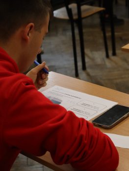 Student in a red sweatshirt working on an exercise sheet during the “Young Masters of Logistics” project